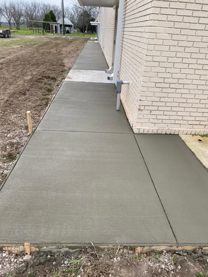 New concrete walkway along a brick house