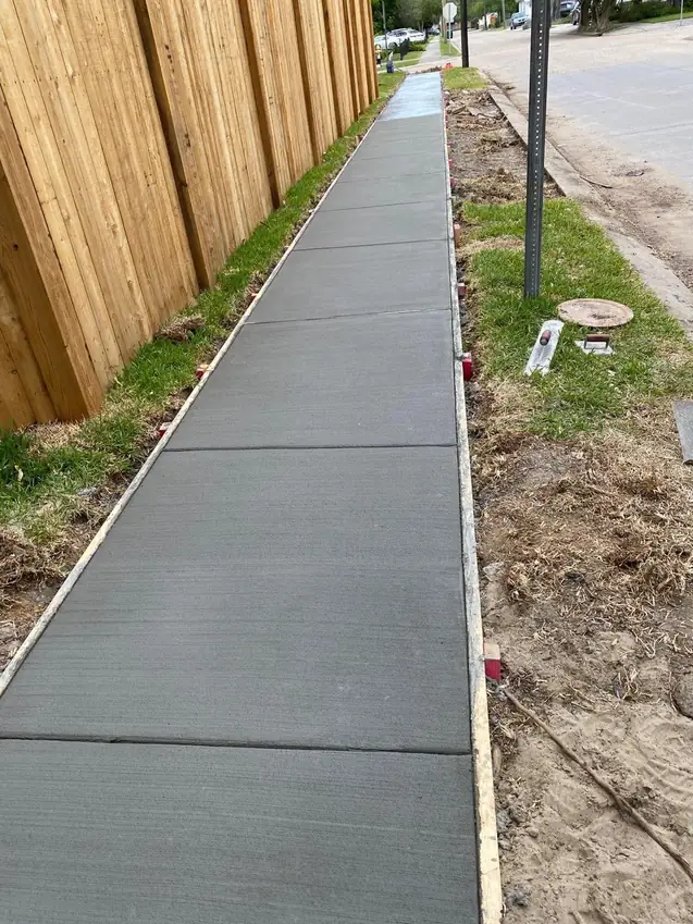 Finished sidewalk beside a wooden fence