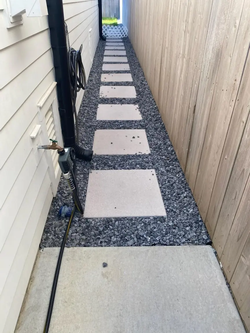 Stepping stones in gravel between a house and fence