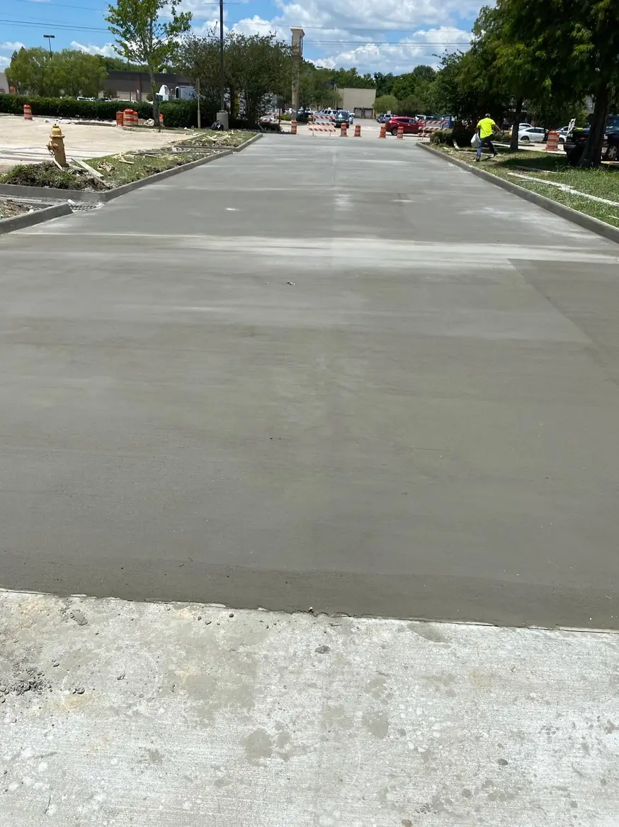 Freshly placed concrete slab with crew in the background