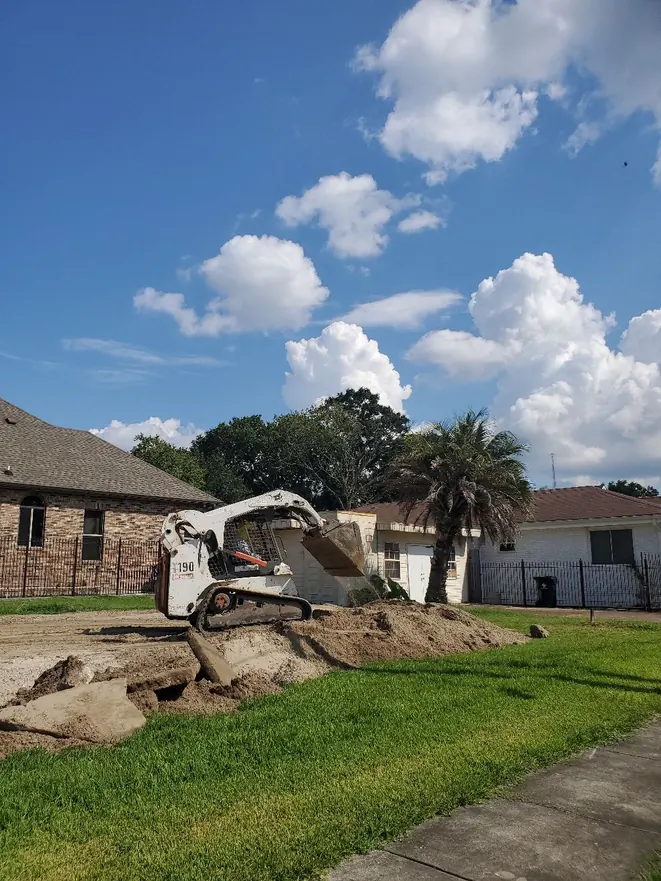 Loader moving soil beside a brick house